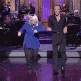 a woman in a blue shirt is dancing with a man in a black shirt behind her