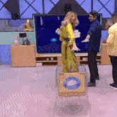 a woman in a yellow dress is standing in front of a box that says famosos on it