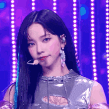 a woman with a microphone in her mouth stands in front of a purple background