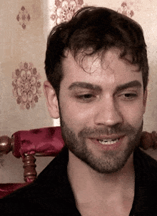 a man with a beard and a black shirt smiles