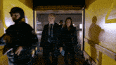 a man and a woman are walking through a hallway with a yellow wall
