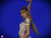 a woman in a white top and silver skirt is dancing on a blue background