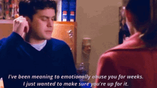 a man in a blue sweater is talking to a woman in a pink coat
