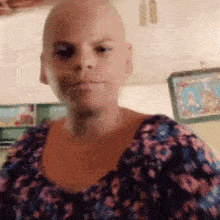 a woman with a bald head is wearing a floral dress .