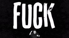 a man stands in front of a black background with skulls and the word fuck