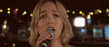 a woman singing into a microphone with a blurred background