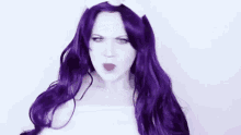 a woman with long purple hair is wearing a white wig and a white hat .
