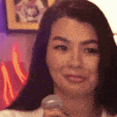 a woman is smiling while holding a microphone in her hand .