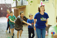 a woman wearing a blue shirt that says autism on it is leading a group of children