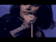 a close up of a person singing into a microphone with a blue background .