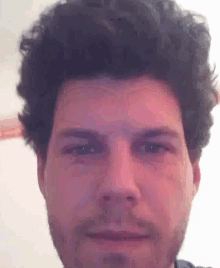 a close up of a man 's face with curly hair and a beard
