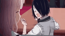 a boy and a girl are sitting at a table talking to each other in a room .