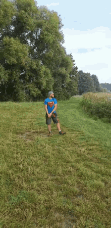 a man in a superman shirt is standing in the grass