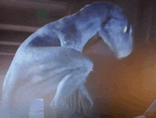 a blue monster is standing in a dark room with a blurred background