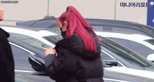 a woman with red hair is wearing a mask and looking at her cell phone