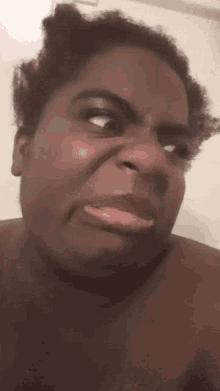 a shirtless woman making a funny face with her tongue sticking out