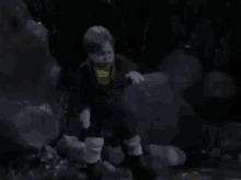 a little boy is standing in the dark with a gun in his hand and screaming .