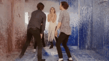 a group of people are dancing in a room that is covered in paint .