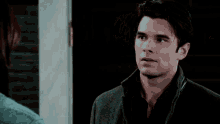 a man in a blue shirt is standing in front of a door and looking out .