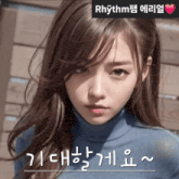a woman in a blue turtleneck sweater with rhythm written on the bottom