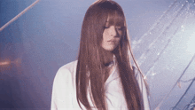 a woman with long brown hair is wearing a white shirt and has her eyes closed
