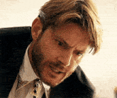 a man in a suit and tie with a beard is making a funny face .