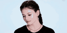 a woman wearing a braided ponytail and a necklace is looking down