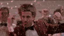 a man in a tuxedo is standing in front of a crowd of people .