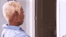 a woman is standing in front of a door wearing hoop earrings .