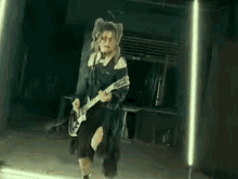 a woman is playing a guitar in a dark room in front of a mirror .