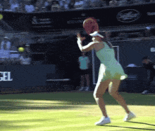 a woman in a green dress is holding a tennis racket on a tennis court