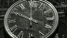 a black and white photo of a clock with roman numerals shows the time as 4:20