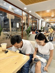 a man and a woman are sitting at a table in a restaurant with a sign that says exit