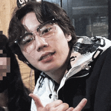 a young man wearing glasses and a black jacket with the letter r on it