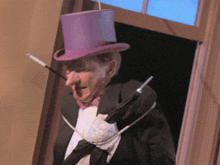 a man in a top hat and tuxedo holds a cane