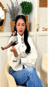 a woman is sitting in a chair holding a doll with the name nessa on her sleeve