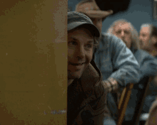 a man in a cowboy hat is peeking out from behind a door