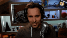 a man wearing headphones is smiling in front of a microphone with a sticker that says ' a ' on it