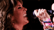 a close up of a woman singing into a microphone with rbd.gif written below her