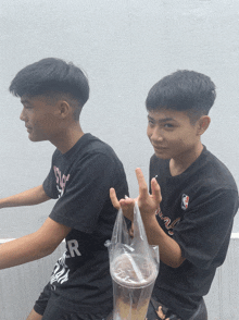 two boys wearing black shirts with the letter r on the back