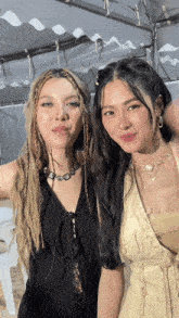 two women posing for a picture with one wearing a necklace with a heart on it