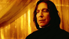 a close up of a man with long hair standing in front of a yellow wall .