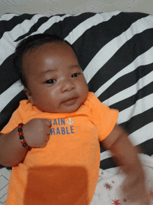a baby wearing an orange shirt that says tain rable on it