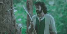 a man is standing in the woods holding a large knife .