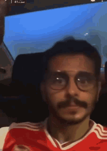 a man wearing glasses and a red shirt with the number 41 on the bottom right