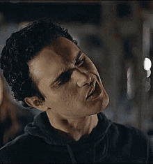 a man in a black hoodie is making a funny face .