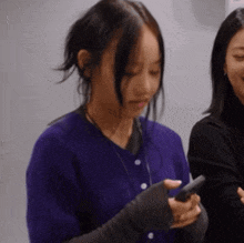 a woman in a purple sweater is holding a cell phone in her hand
