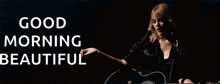 a woman is singing into a microphone while holding a guitar in front of a sign that says " good morning beautiful "