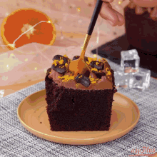 a piece of chocolate cake is being eaten with a fork on a wooden plate