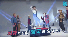 a group of people are dancing on a stage with korean writing on the bottom